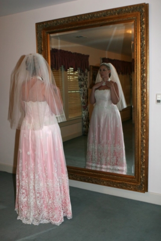 Bride looking in mirror wearing a pink ombre wedding gown