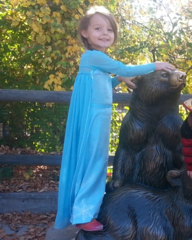 young girl wearing a teal Elsa costume from the movie Frozen.